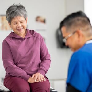 Smiling Senior Patient With Medical Professional During Routine Checkup In Bright Clinic Exam Room